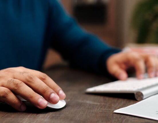 Close-up of a hand using a wireless mouse and keyboard at an office desk