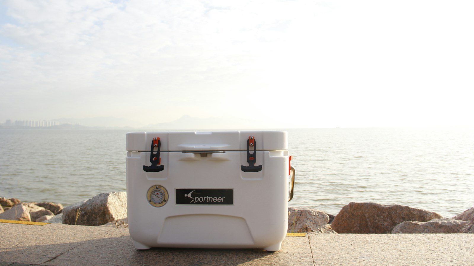 Portable cooler box beside water for a day trip