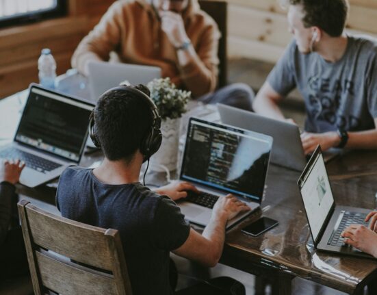 Small team collaborating around a laptop to evaluate an AI workspace