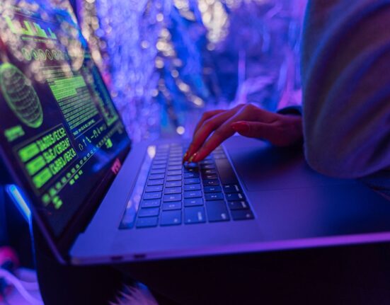 Hands typing on a laptop with cybersecurity graphics, illustrating antivirus vs internet security suite
