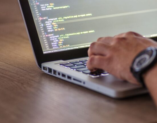 Person typing code on a laptop representing antivirus vs internet security suite in the United Kingdom