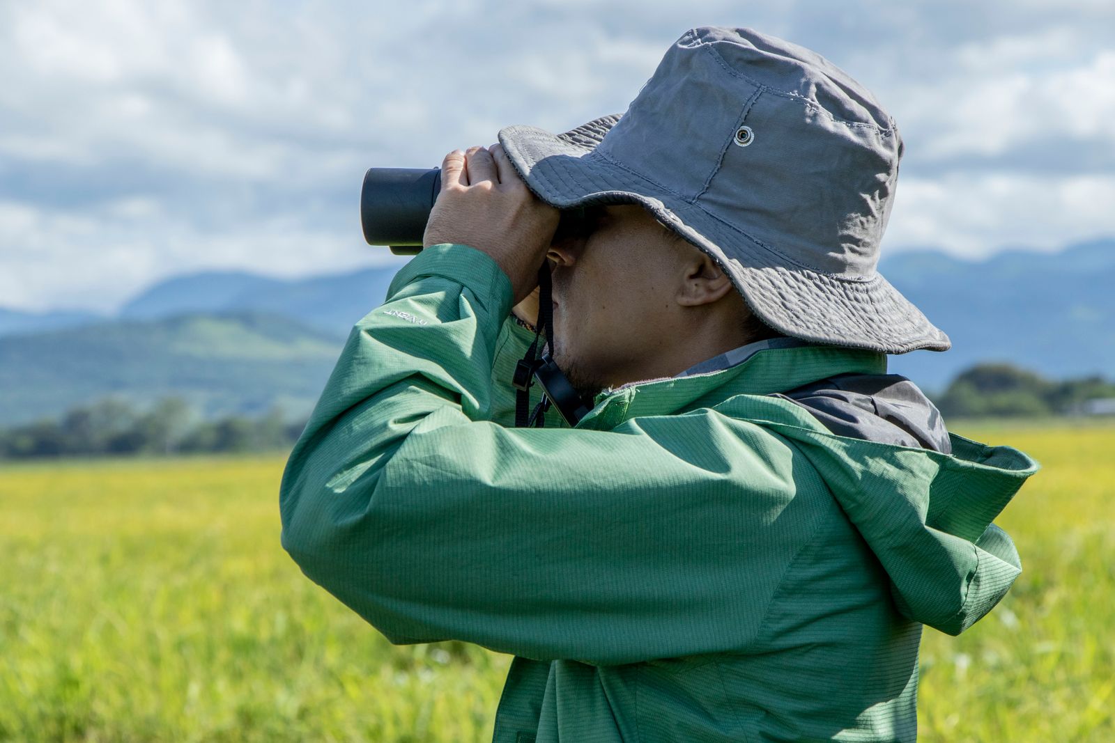Close-up of a birdwatcher holding binoculars outdoors