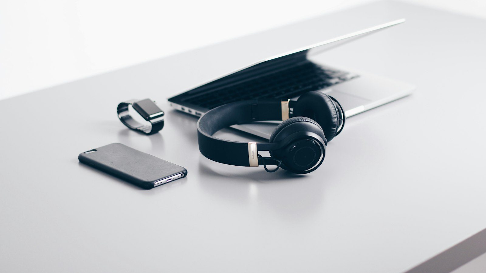 Laptop, headphones and phone on a clean desk for an ecommerce promo video workflow in Canada