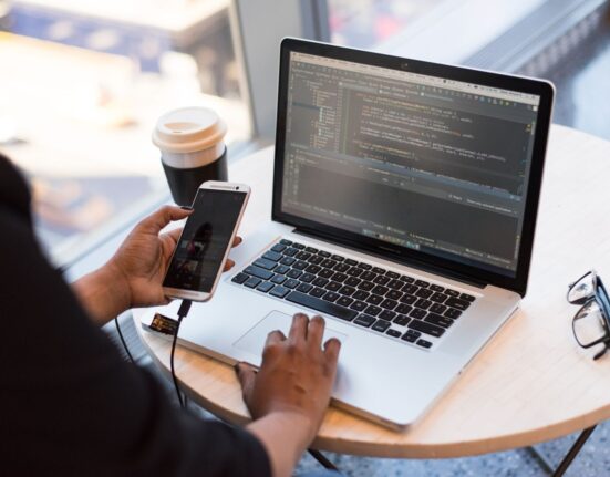 Professional managing email on a laptop and phone to compare email archiving vs bulk deletion