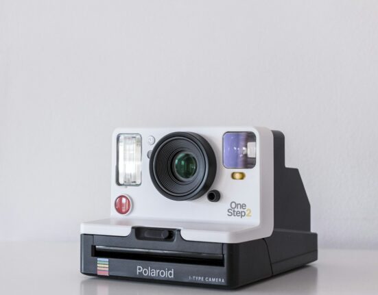 Instant camera on a white table representing product photos for AI promotional videos in Canada