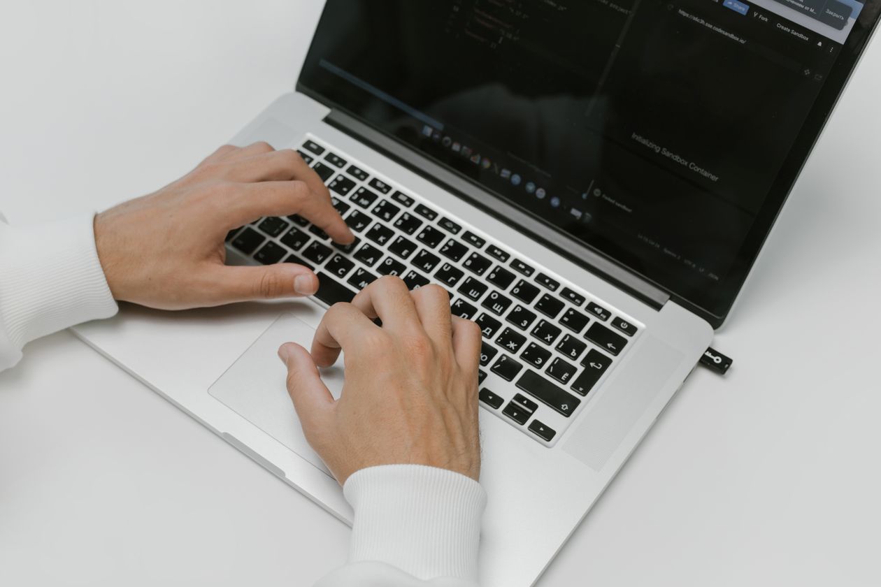 Hands typing on a laptop keyboard for a security suite feature comparison in the UK
