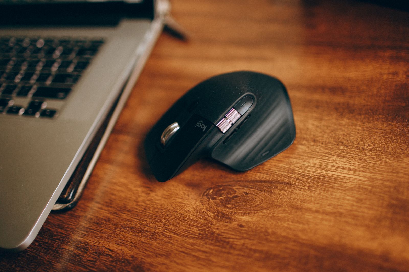 Wireless computer mouse on a desk next to a laptop in a home office